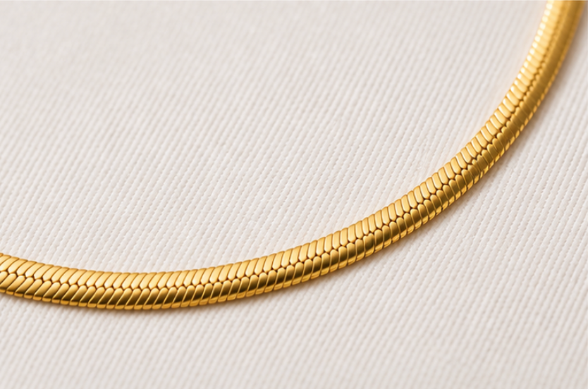 Gold snake chain necklace on a light gray background